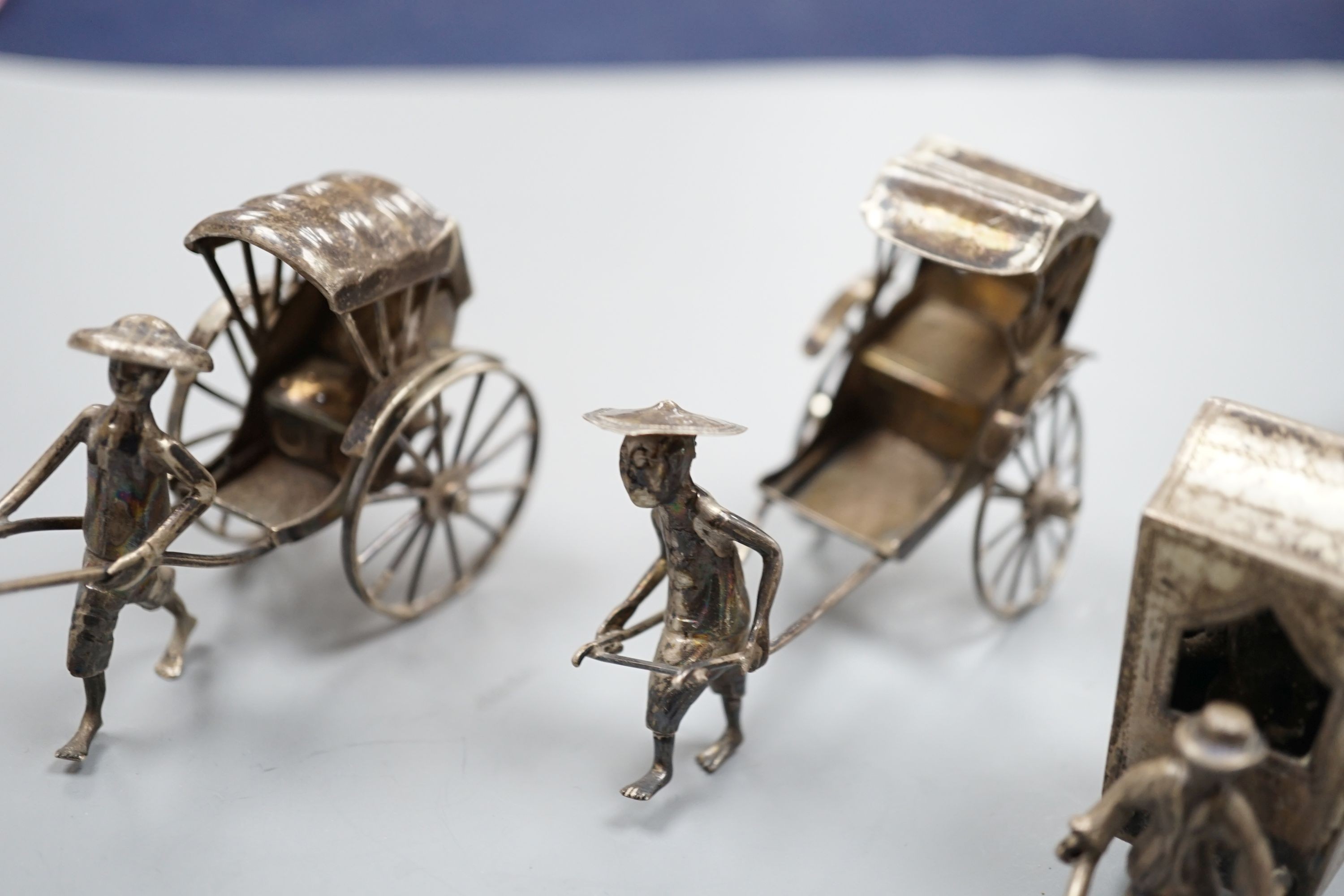 Two early 20th century miniature Chinese white metal models of a figure and rickshaw, by Wang Hing, length approx. 74mm. two other similar Chinese items and and unmarked miniature carriage.